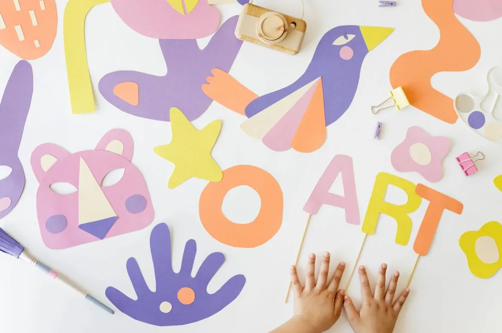 Mains d'enfant sur une table couverte de découpages colorés en papier