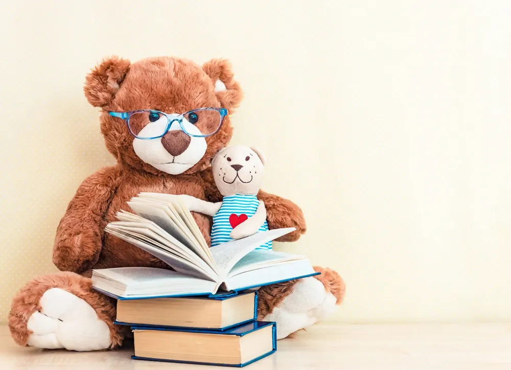 Ours en peluche à lunettes lisant un livre avec un petit ourson