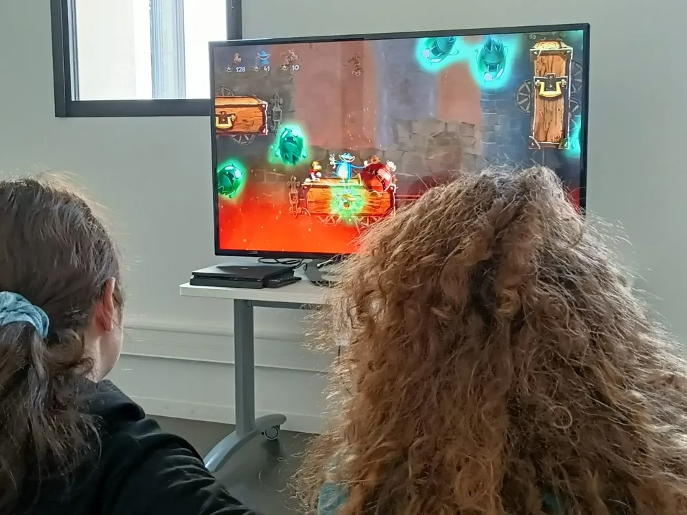 Deux enfants jouant à un jeu de plateforme sur console dans la salle dédiée